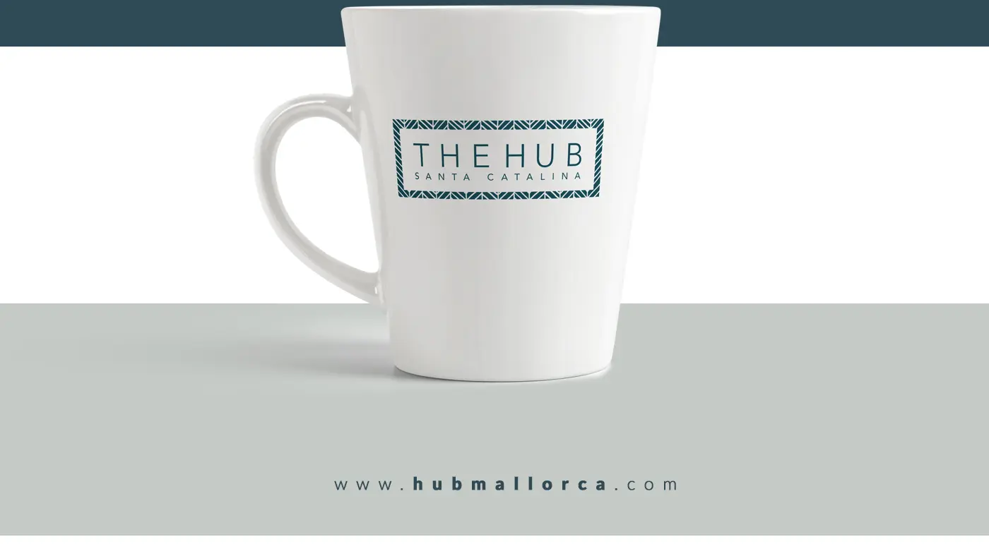 Taza blanca con el logotipo The Hub Santa Catalina en azul petróleo