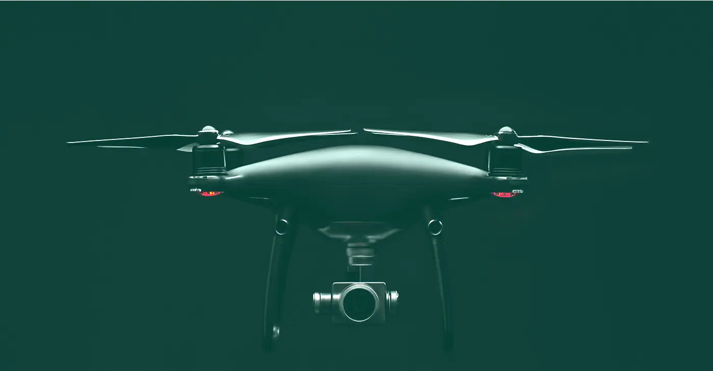 Fotografía de un dron con cámara suspendido sobre fondo verde oscuro