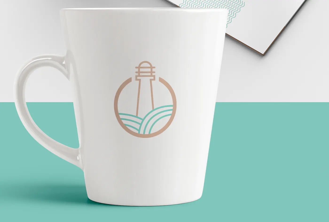 Mockup of a white mug with the lighthouse-and-waves symbol in beige and turquoise