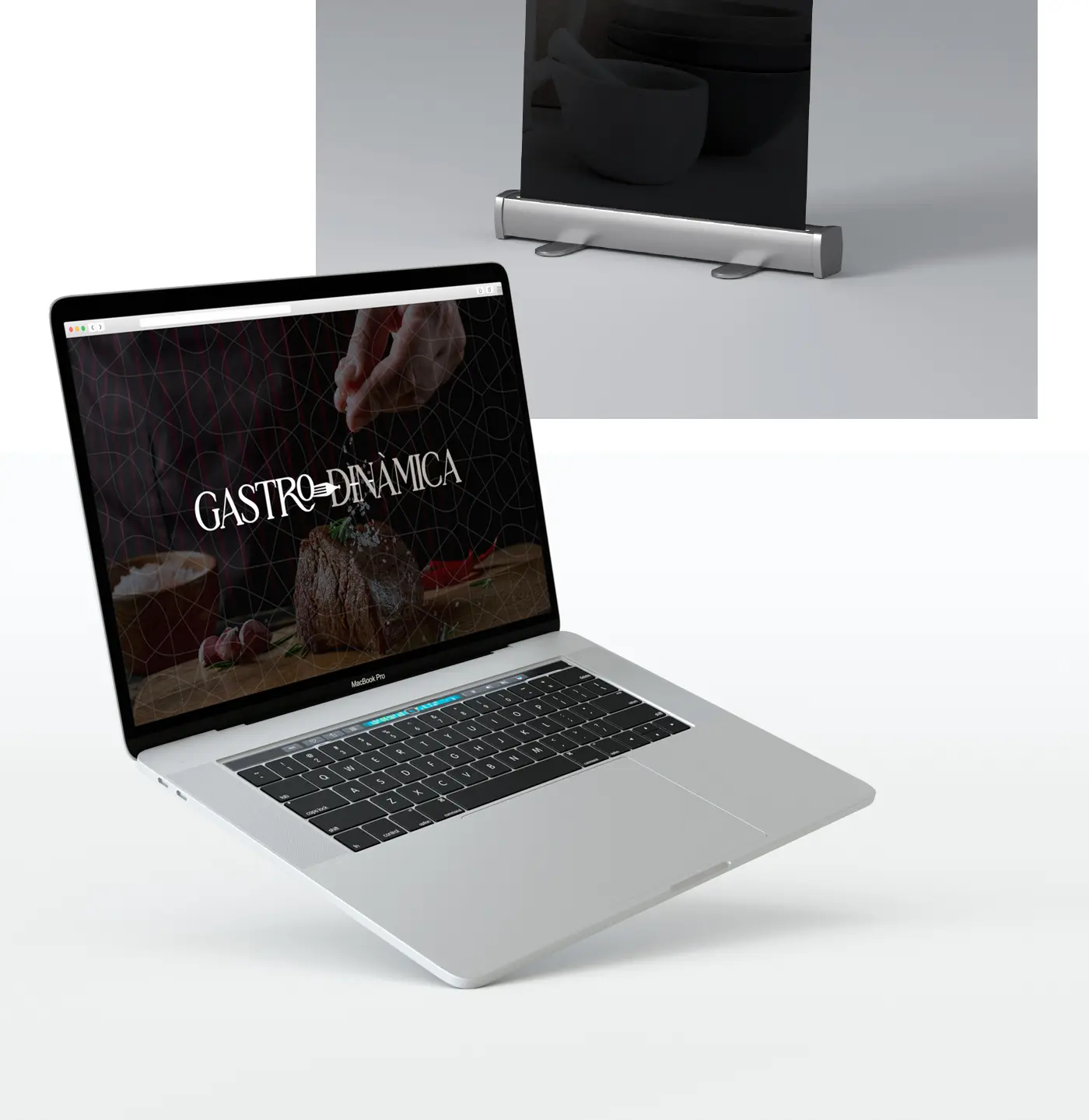 Web de Gastrodinàmica en un MacBook junto a un roll-up con mortero y cuencos de cerámica