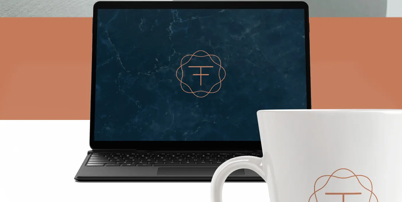 Laptop and white mug with the logotype's symbol over a blue marble background