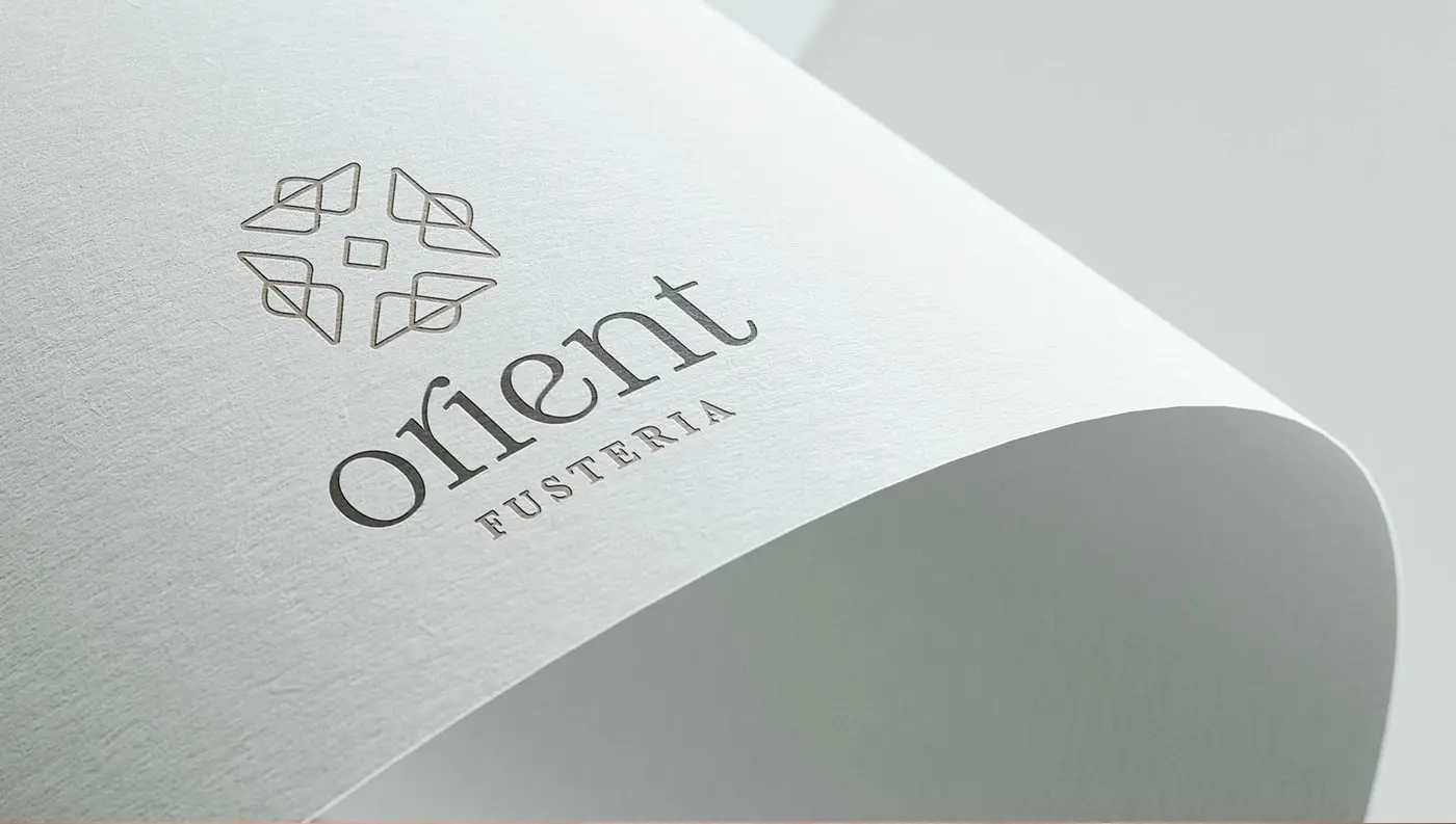 Logotip de Fusteria Orient gravat en relleu sobre paper texturitzat blanc