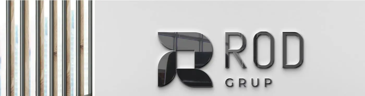 Logotip corporatiu en relleu metàl·lic sobre una paret junt a un tancament de fusta