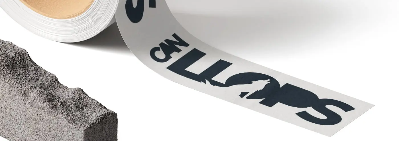 Rollo de cinta adhesiva con el logotipo junto a un bloque de hormigón