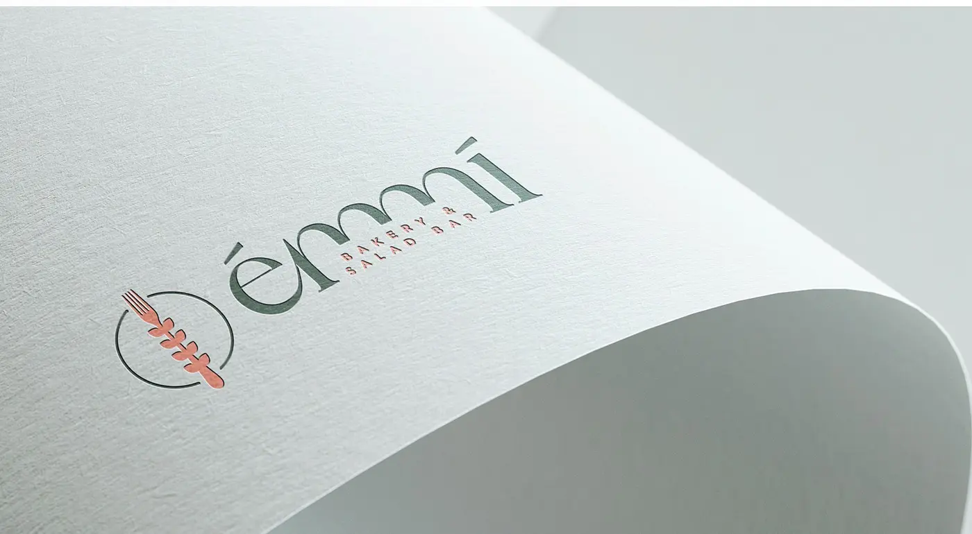 Émmí logo embossed in green and coral relief on textured paper