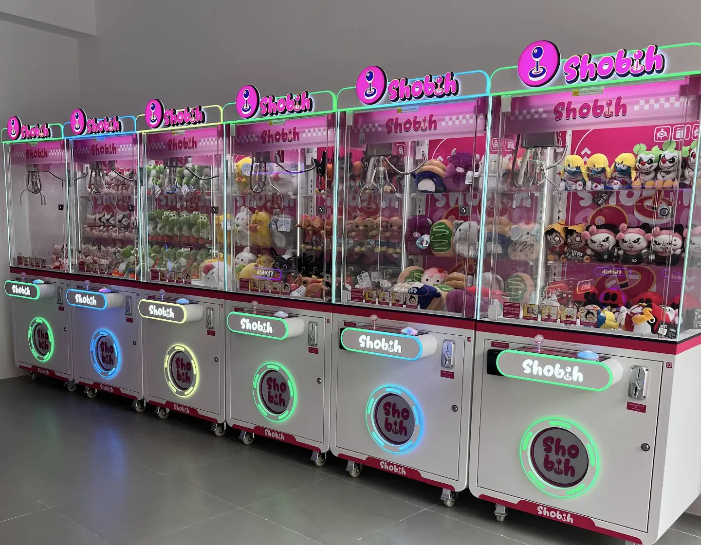 Fila de máquinas expendedoras de peluches con luces de colores en la tienda