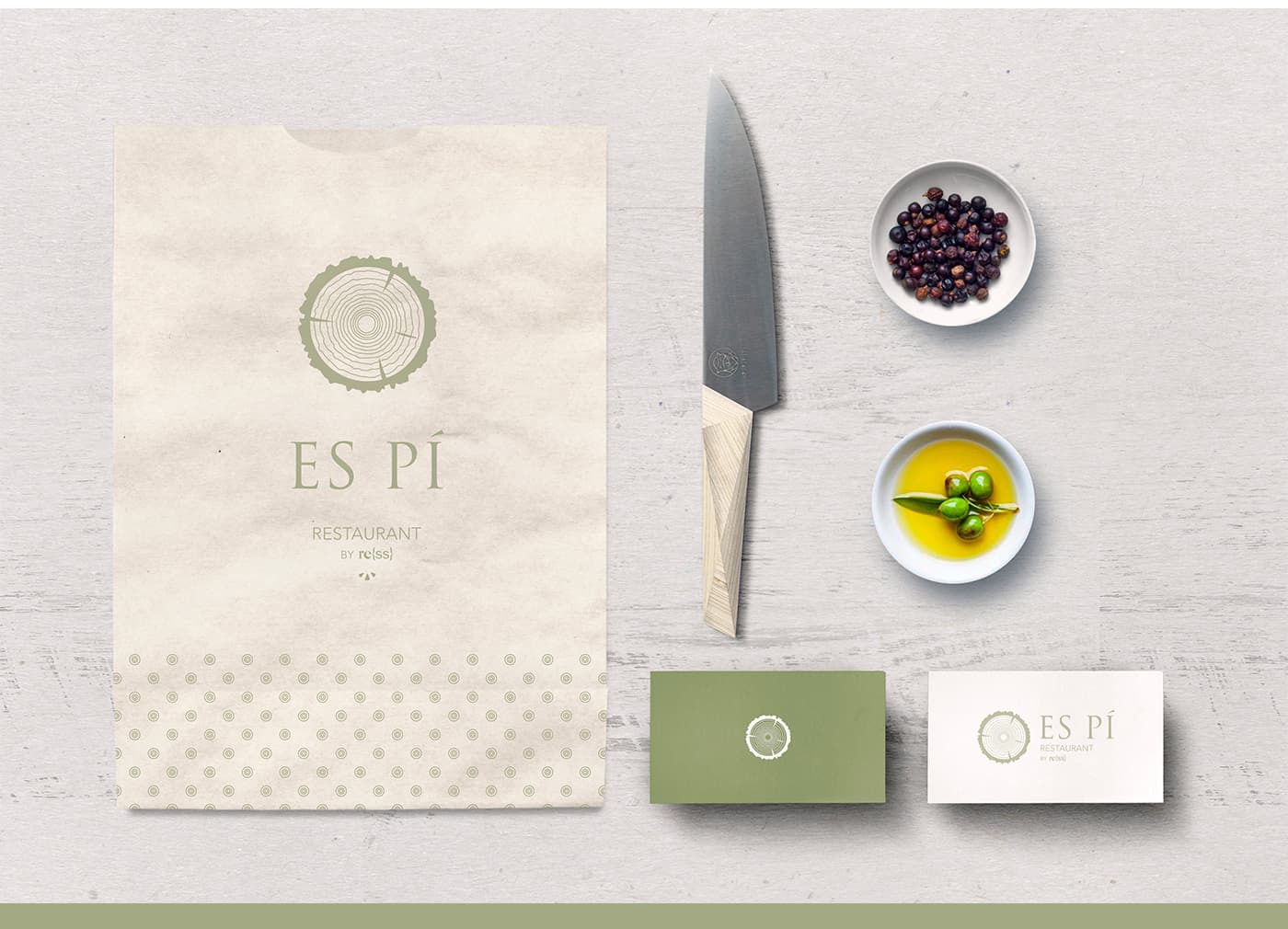 Bossa de paper, ganivet i targetes de visita d'Es Pí al costat d'olives i fruits secs