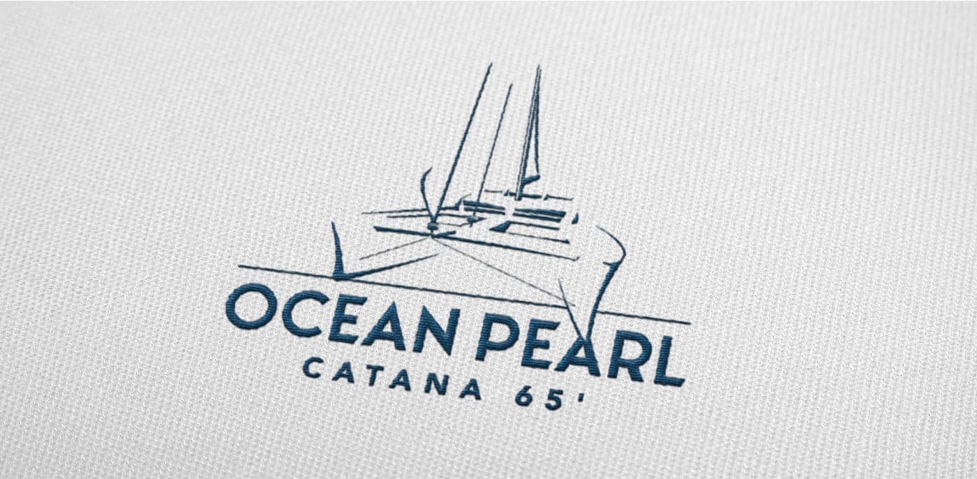 Detail of the logo with the catamaran's linear illustration embroidered on light fabric