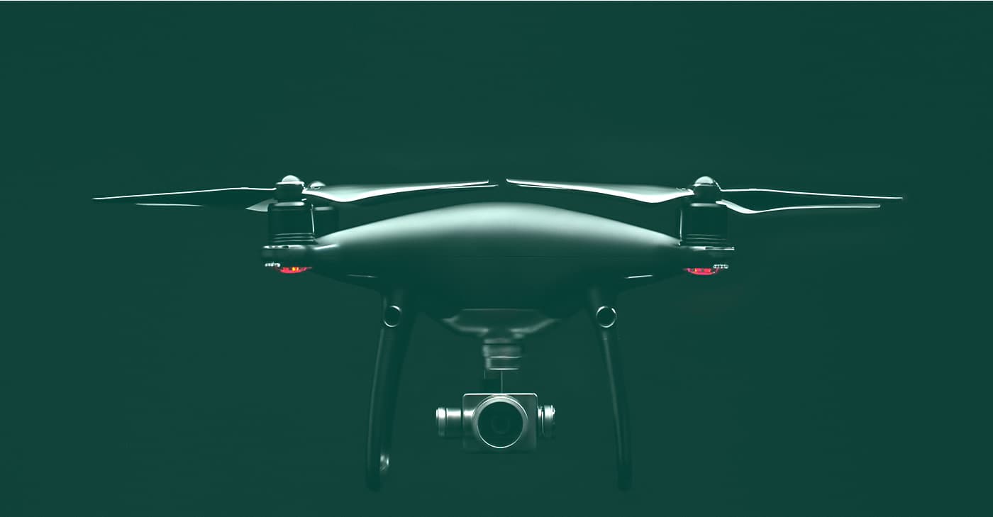 Fotografia d'un dron amb càmera suspès sobre fons verd fosc