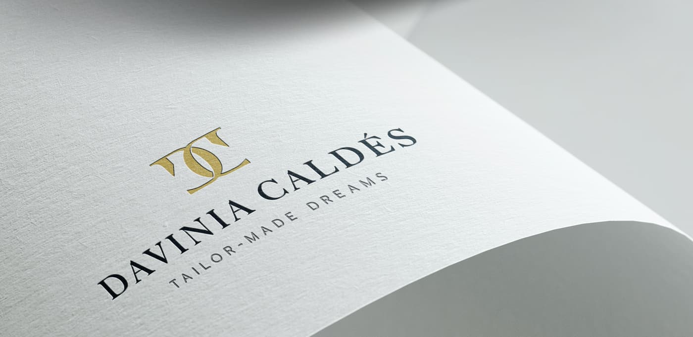 Logotipo grabado en relieve dorado sobre papel texturizado blanco