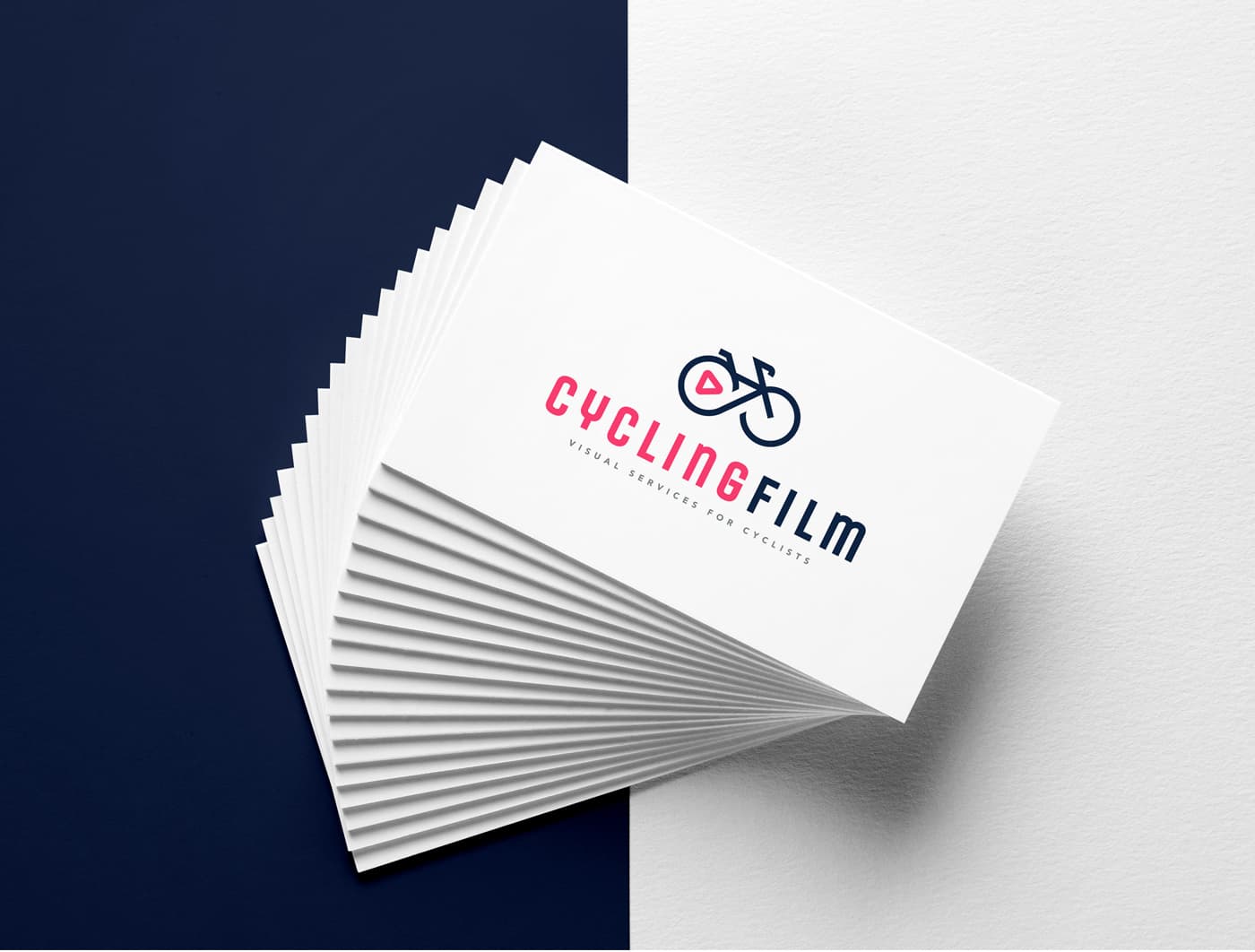 Stacked business cards with the logo in pink and navy-blue ink