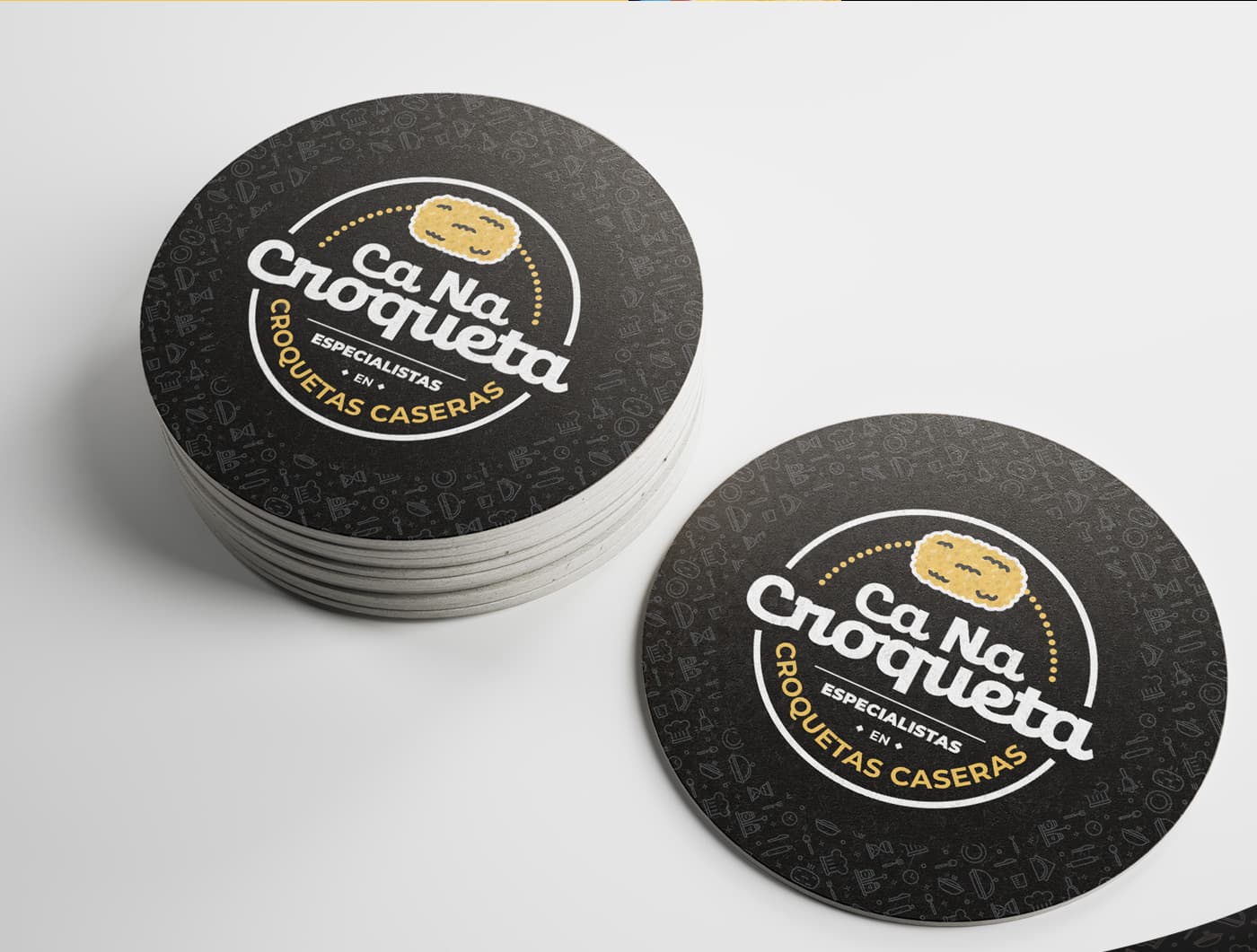 Posavasos redondos en negro con el logotipo de Ca Na Croqueta