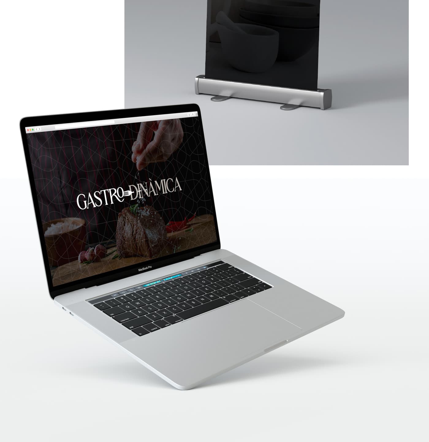 Web de Gastrodinàmica en un MacBook al costat d'un roll-up amb morter i bols de ceràmica