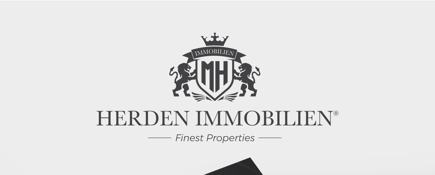 Logotipo de Herden Immobilien con escudo, corona y leones heráldicos en gris oscuro