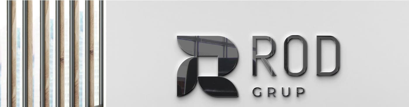 Logotip corporatiu en relleu metàl·lic sobre una paret junt a un tancament de fusta
