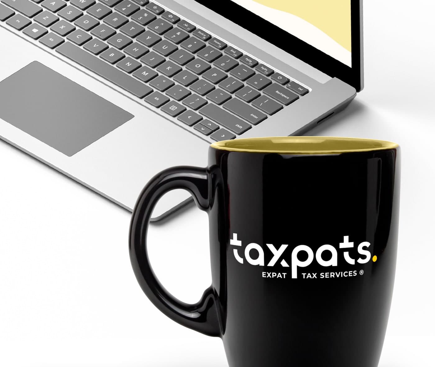Tassa negra amb el logotip Taxpats al costat d'un ordinador portàtil