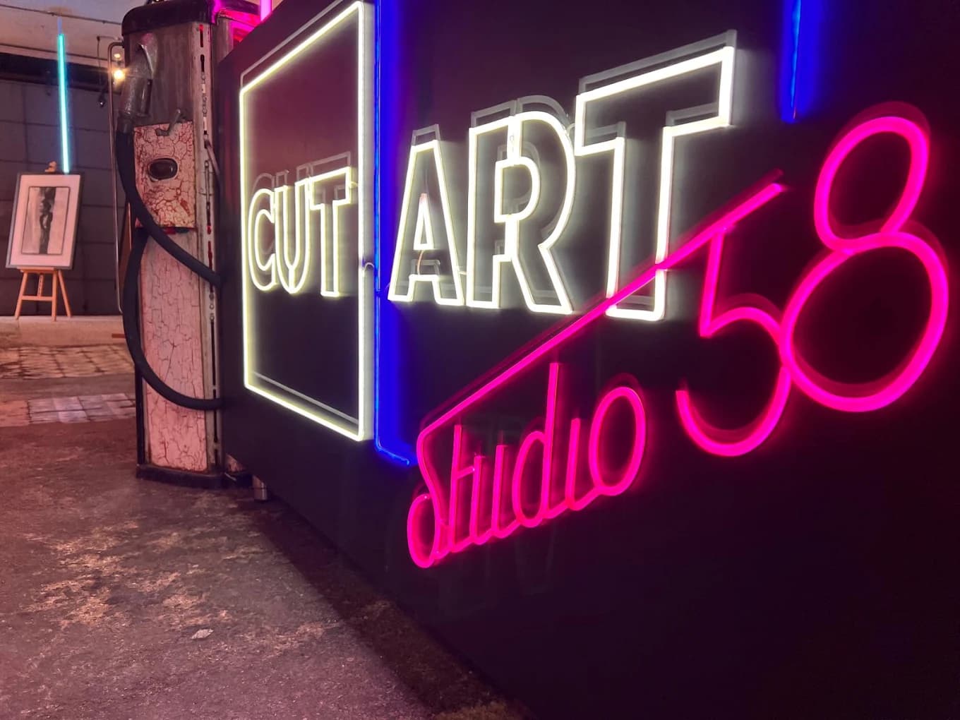 Illuminated CUT ART Studio 58 neon sign at the venue, next to an old fuel pump