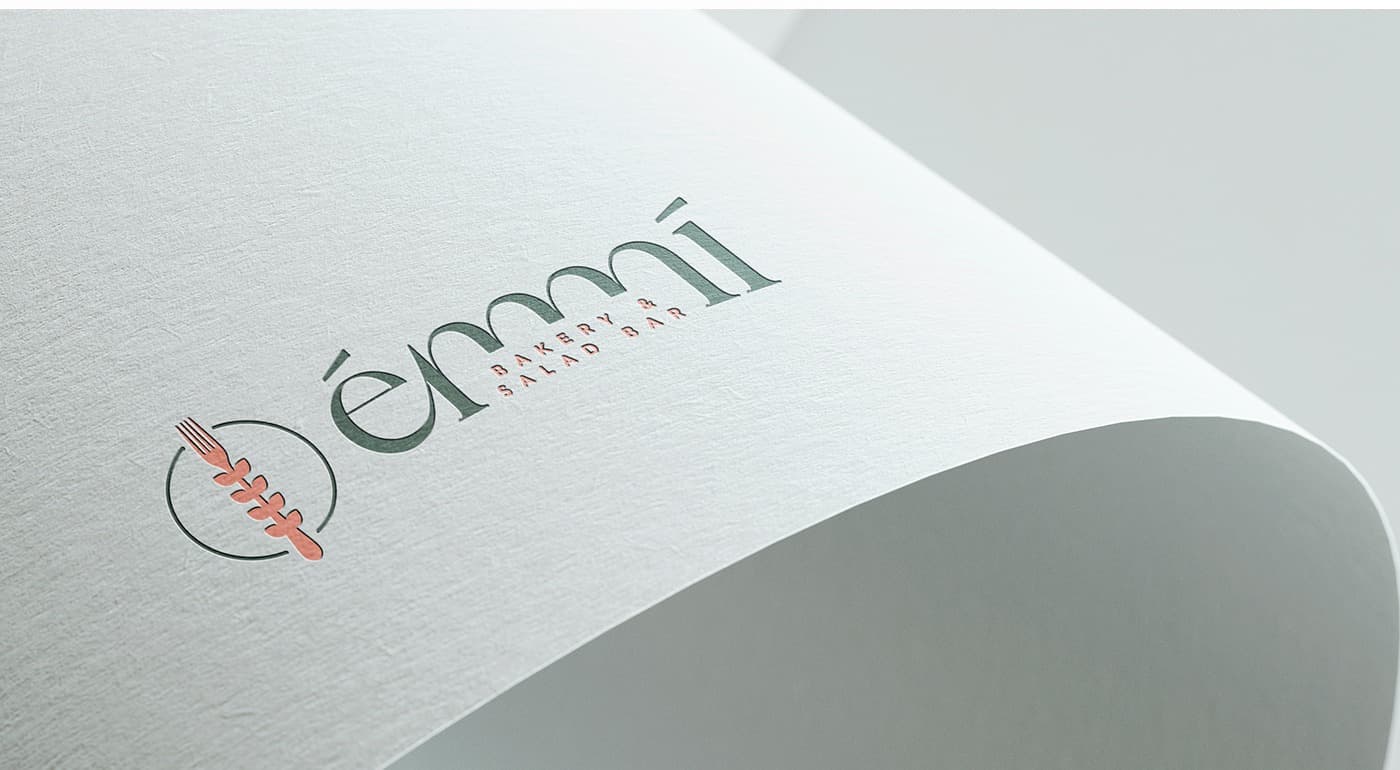 Logotipo de Émmí grabado en relieve verde y coral sobre papel texturizado