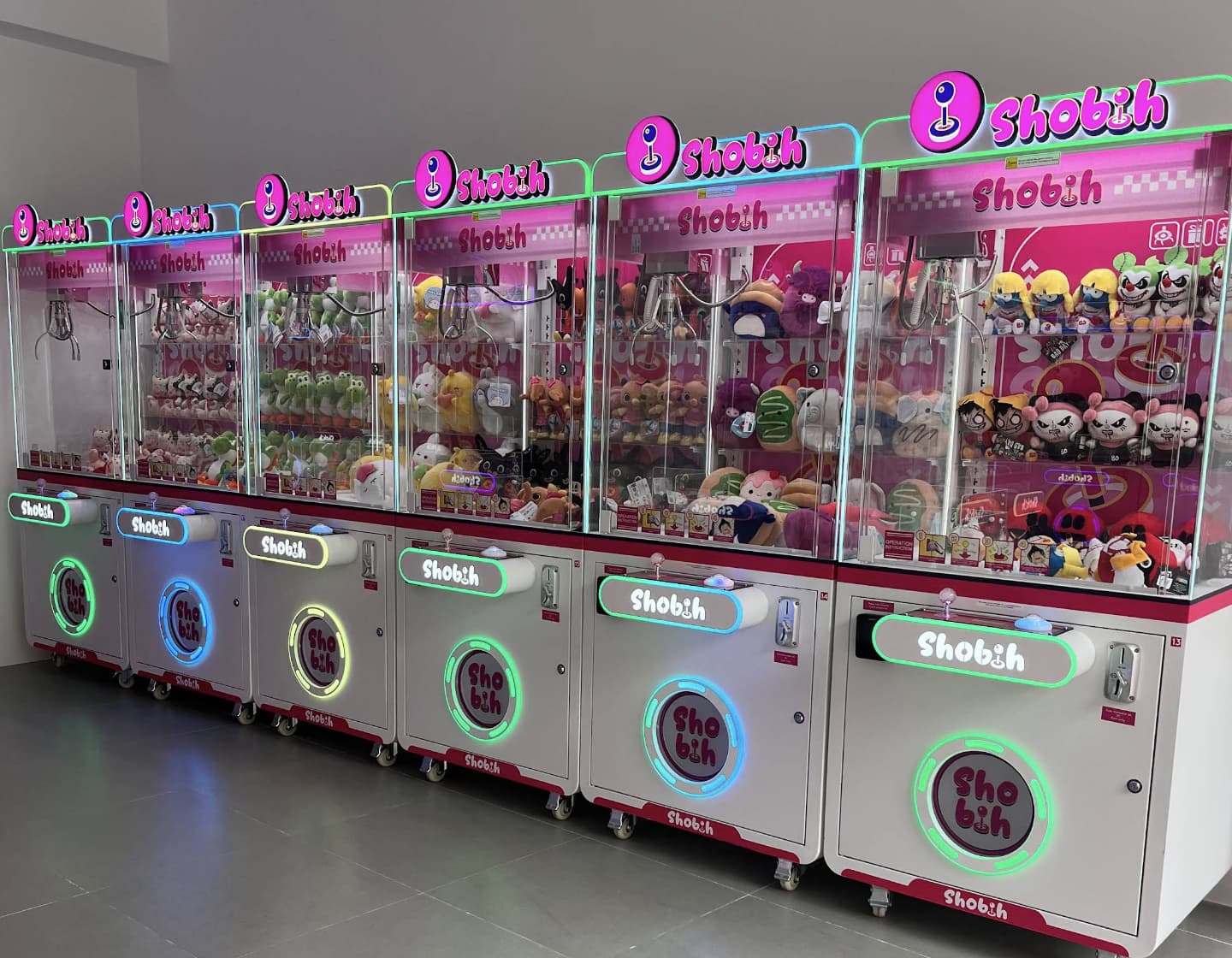 Fila de máquinas expendedoras de peluches con luces de colores en la tienda